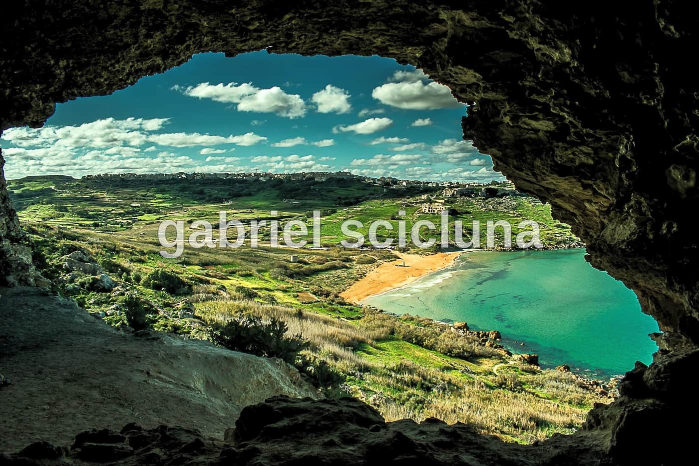 The striking view through Mixta Cave towards the turquoise waters and coastline of Gozo.
