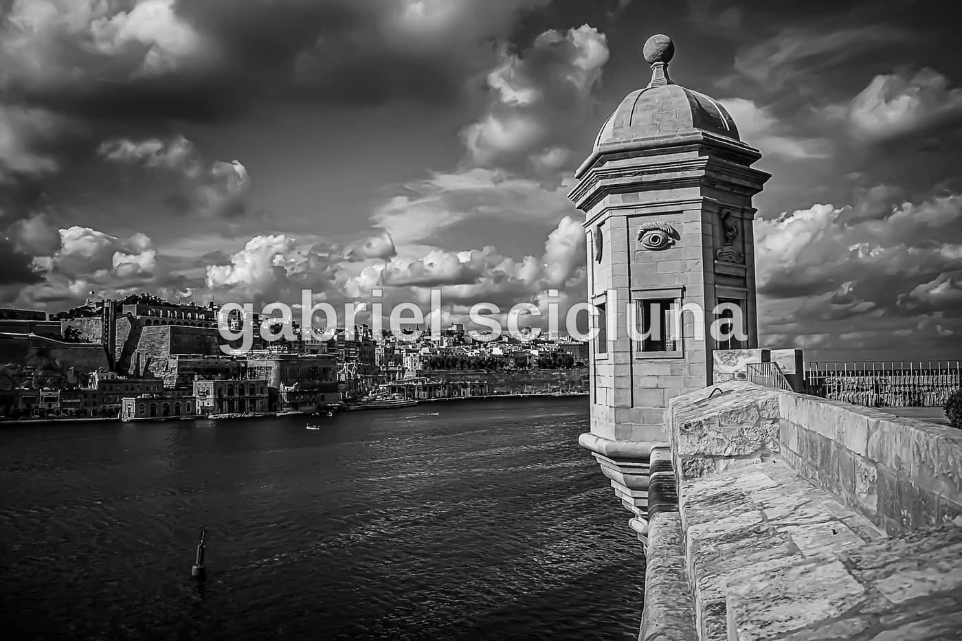 A monochrome photographic study of stone sculpture and a fountain in the Maltese Islands.